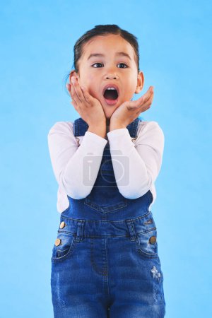 Photo for Shocked, wow and girl with hands to face in studio with fear and scared from danger. Alarm, blue background and young child from Hawaii with scary, omg surprise and emoji face of a kid in danger. - Royalty Free Image