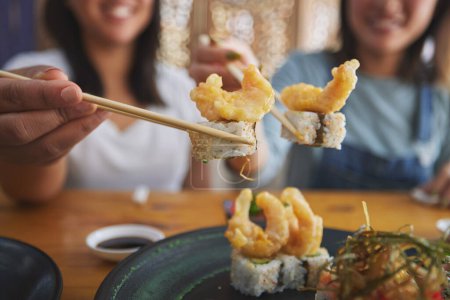 Photo for Chopsticks, woman hands and shrimp sushi closeup at a table with Japanese cuisine food at restaurant. Young women, eating and tempura prawn with fish for lunch and meal on a plate with a smile. - Royalty Free Image