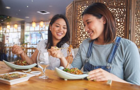 Foto de Restaurante, amigas y hablar con la comida, fideos y café feliz de la vinculación. Las mujeres asiáticas, comiendo y plato junto con la sonrisa de amistad en una mesa hambrienta de palillos en el bar japonés. - Imagen libre de derechos