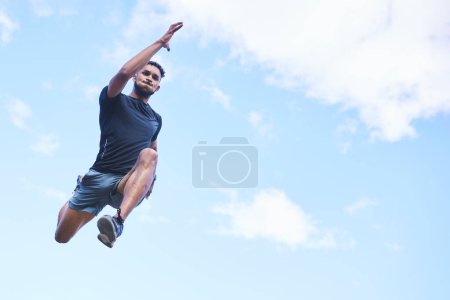 Hombre corredor, salto y cielo con espacio para maqueta, nubes y fitness en naturaleza, acción y libertad. Tipo atleta, ángulo bajo y al aire libre para el entrenamiento, ejercicio y entrenamiento con movimiento rápido para la salud.
