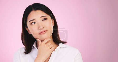 Photo for Asian woman, thinking and decision on mockup space in problem solving against a pink studio background. Female person with idea, solution or choice in memory, reminder or brainstorming on mock up. - Royalty Free Image