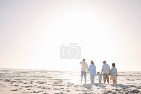 Téléchargez les photos : Espace, voyager et se tenir la main avec une grande famille sur la plage pour des vacances, des liens et de l'amour. Été, soins et détente avec un groupe de personnes marchant à la mer vacances pour les générations, bonheur et maquettes. - en image libre de droit