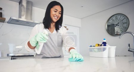 Photo for Happy woman, housekeeper and cleaning kitchen table with spray bottle, detergent or bacteria and germ removal at home. Female person maid or cleaner wiping surface with cloth in hygiene or sanitise. - Royalty Free Image