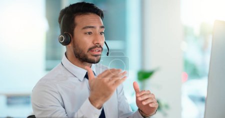 Photo for Call center agent consulting a buyer via video call in an office. A young friendly sales man talking to a client in a virtual meeting. A male customer service employee advising a consumer. - Royalty Free Image