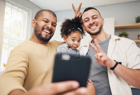 Photo for Selfie, blended family and a happy girl with her lgbt parents in the kitchen together for a profile picture. Adoption photograph, smile or love and a playful daughter with her gay father in the home. - Royalty Free Image