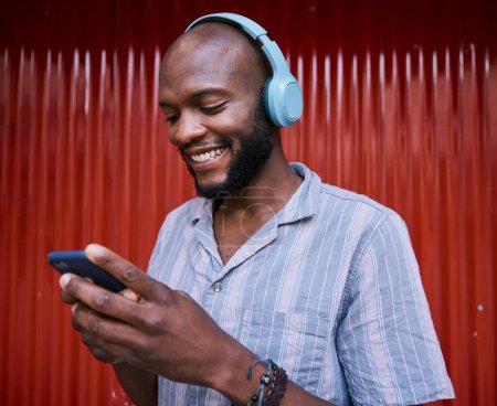 Photo for Black man, smartphone and headphones, smile with technology and listening to music or podcast. Communication, social media and online chat, audio streaming and subscription with network and gen z. - Royalty Free Image