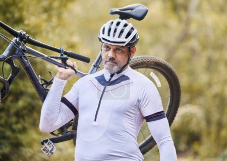 Photo for Athlete, man and carrying mountain bike outdoor for cardio exercise, sports race and training in nature. Mature cyclist walking with bicycle, focus and thinking of cycling adventure on off road path. - Royalty Free Image