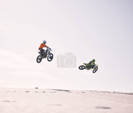 Téléchargez les photos : Dune, saut et hommes en moto ensemble pour la pratique, l'entraînement et l'énergie sportive extrême dans la nature. Défi professionnel de vélo de saleté, amis et danger avec la compétition de moto sur la colline du désert - en image libre de droit