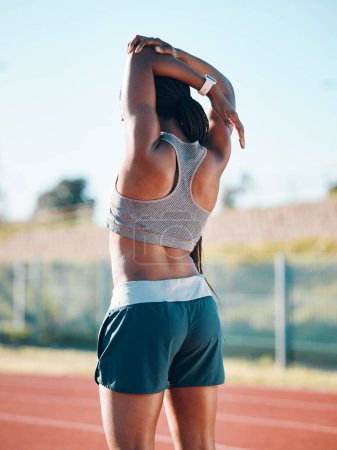 Photo for Stretching, sports and exercise with a woman outdoor on a track for running, training or workout. Behind African athlete person at stadium for arm stretch, fitness and muscle warm up or body wellness. - Royalty Free Image