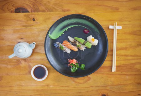 Téléchargez les photos : Sushi, nourriture et baguettes dans un restaurant asiatique d'en haut pour une cuisine raffinée ou traditionnelle. Saumon, menu et fruits de mer avec un plat chinois sur une table dans un restaurant local pour la faim ou la nutrition. - en image libre de droit