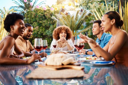 Téléchargez les photos : Des gens heureux à table, déjeuner dans le jardin et conversation bbq événement avec la diversité, la nourriture et le vin. Dîner en plein air, hommes et femmes ensemble, amis manger avec parler dans la cour en été - en image libre de droit