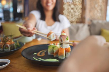 Photo for Hands, chopsticks and sushi restaurant with friends, smile and excited for fine dining, party and share. Happy women, fish and healthy with culture, traditional or fast food in diner, bar or shop. - Royalty Free Image