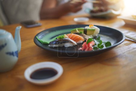 Téléchargez les photos : Sushi, nourriture et baguettes dans un restaurant chinois à proximité pour une cuisine raffinée ou traditionnelle. Saumon, menu et fruits de mer avec un plat asiatique sur une table dans un restaurant local pour la faim ou la nutrition. - en image libre de droit