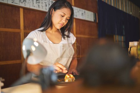 Téléchargez les photos : Nourriture chinoise, recette et une femme asiatique dans un restaurant de sushi pour servir un repas traditionnel pour la nutrition. Cuisine, cuisine ou préparation avec une jeune femme chef dans un restaurant pour une cuisine gastronomique. - en image libre de droit