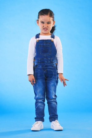 Photo for Angry, attitude and portrait of child on blue background with upset, mad and frustrated facial expression. Behaviour, youth and young girl with body language for anger, tantrum and emotion in studio. - Royalty Free Image