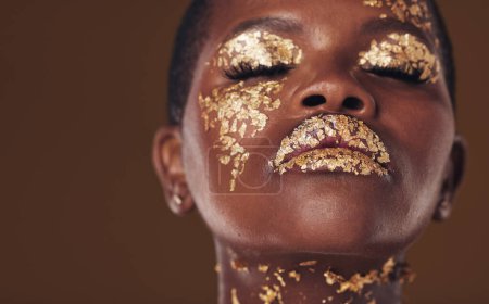 Téléchargez les photos : Or, art et visage de femme africaine maquillée pour une esthétique beauté isolée dans un studio brun les yeux fermés. Créatif, luxueux et personne avec glamour cosmétique ou design pour les soins de la peau. - en image libre de droit
