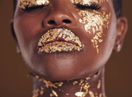 Téléchargez les photos : Or, créatif et visage de femme noire avec maquillage pour une esthétique beauté isolée dans un studio brun les yeux fermés. Art, luxe et Africain avec glamour cosmétique ou design pour les soins de la peau. - en image libre de droit