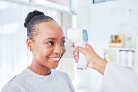 Photo for Black woman, doctor and infrared thermometer for temperature, fever or checkup at the hospital. Happy African female person or patient smile in screening, visit or regulation for health and safety. - Royalty Free Image