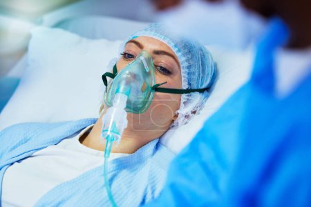 Photo for Hospital, anesthesia and woman with oxygen mask in surgery for medical service, operation and procedure. Healthcare, doctor and surgeons with gas, breathing and ventilation equipment for patient. - Royalty Free Image