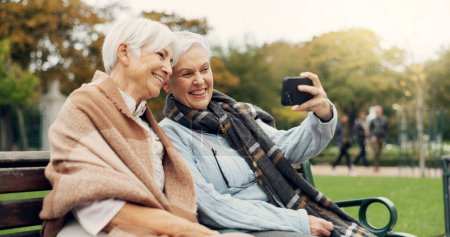 Photo for Senior, women and selfie in a park happy, bond and relax in nature on a bench together. Friends, old people and ladies smile for social media, profile picture or memory in forest chilling on weekend. - Royalty Free Image