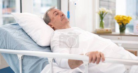 Photo for Man, cancer and patient in hospital bed thinking about healthcare, wellness and healing in clinic after surgery. Medical treatment, sick and person with health problem in hospice for recovery in icu. - Royalty Free Image