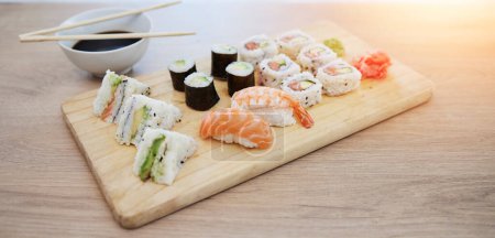 Photo for Sushi, seafood and wood board, soy sauce and closeup, salmon and rice with avocado, healthy and luxury. Japanese cuisine, catering with lunch or dinner meal, chopsticks and food with nutrition. - Royalty Free Image