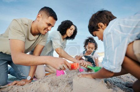 Photo for Parents, children and sandcastle at beach, bucket and digging for bonding, outdoor and vacation in summer. Mother, father and kids with plastic toys, sand and games on holiday, teamwork and ocean. - Royalty Free Image