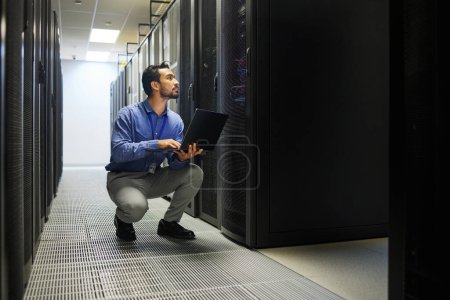 Server room, laptop or man typing for cybersecurity glitch, machine or to search online on servers system. IT support, data center or male engineer fixing network for information technology solution.