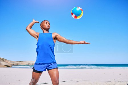 Téléchargez les photos : Le volleyball de plage, le sport et l'homme noir servent le ballon, jouent la compétition et l'entraînement d'athlète dans le défi extérieur. Ciel bleu, liberté et entraînement des joueurs africains, exercice et début de jeu, match ou pratique. - en image libre de droit
