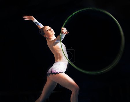 Photo for Portrait, training with a gymnastics hoop and a woman in the gym for a performance showcase or practice. Fitness, dance and concert with a female athlete on a dark background for routine or recital. - Royalty Free Image