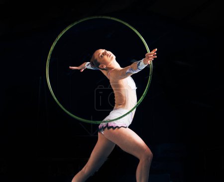 Photo for Dance, training with a gymnastics hoop and a woman in the gym for a performance showcase or practice. Fitness, energy and concert with a female athlete on a dark background for routine or recital. - Royalty Free Image
