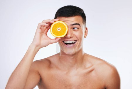 Photo for Beauty, orange and happy with face of man in studio for health, detox and natural cosmetics. Vitamin c, nutrition and summer with face of person and fruit on white background for self care and glow. - Royalty Free Image