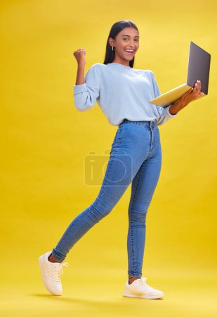 Photo for Woman, student and winner on laptop for success, university news and e learning results or opportunity in studio. Person in college portrait with yes, wow or winning on computer and yellow background. - Royalty Free Image