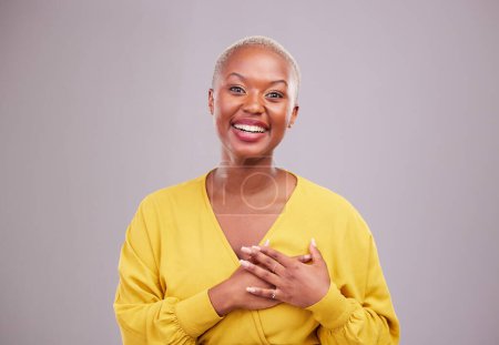 Téléchargez les photos : Merci, sourire et portrait d'une femme noire dans un studio avec une attitude douce, heureuse et positive. Empathie, gratitude et jeune modèle féminin africain avec geste reconnaissant isolé par fond gris. - en image libre de droit