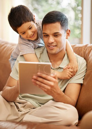Photo for Happy father, kid and hug with tablet in home for online games, reading ebook story and elearning multimedia. Man, dad and boy child watch cartoon, movies or digital technology on sofa in living room. - Royalty Free Image