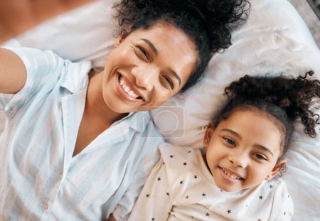 Photo for Top view, selfie and mother with girl child on a bed happy, bond and relax at home. Love, profile picture and kid with mom influencer smile for social media, blog or podcast post or bedroom memory. - Royalty Free Image