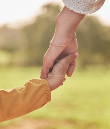 Photo for Mother, child and holding hands for walking in park for support, trust and care together or bonding in nature. Love, comfort and parent help kid in the morning sunshine with kindness on weekend. - Royalty Free Image