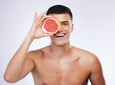 Photo for Beauty, grapefruit and skincare with portrait of man in studio for health, detox and natural cosmetics. Vitamin c, nutrition and spa with person and fruit on white background for self care and glow. - Royalty Free Image