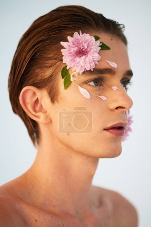Photo for Beauty, petals and flowers on face of man in studio for spring, natural cosmetics and creative. Glow, self love and floral with model on white background for makeup, spa treatment and wellness. - Royalty Free Image