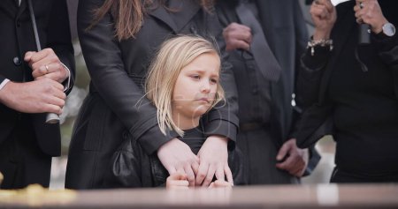 Child, sad and family at funeral at graveyard ceremony outdoor at burial place. Death, grief and group of people with casket or coffin at cemetery for service while mourning a loss at event or grave.