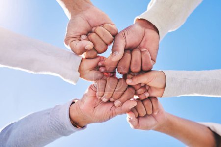 Photo for Hands in circle, blue sky and diversity for community in collaboration for global support and success. Teamwork, fist and bottom view of group of friends with positive vision, trust and love outdoors. - Royalty Free Image