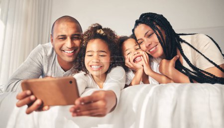 Photo for Happy, bed and selfie of family at home in morning for social media, memory and love. African woman, man and kids lying in bedroom for profile picture, vacation and relax with mother and father. - Royalty Free Image