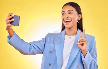Photo for Business woman, selfie and peace sign in studio, smile or excited for review, post or blog by yellow background. Entrepreneur, icon or happy for memory, photography or profile picture on social media. - Royalty Free Image