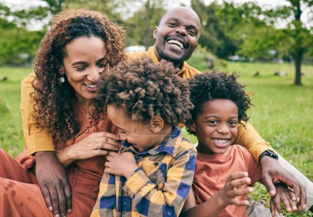 Téléchargez les photos : Bonne famille noire, parents et enfants dans un parc en été, sourire et se détendre sur le champ d'herbe pour l'amour et le plaisir dans la nature. Bonheur, pique-nique et portrait de personnes africaines en plein air et jouer ensemble. - en image libre de droit