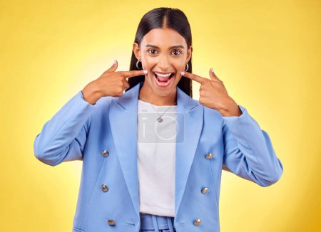 Photo for Fingers on cheek, portrait and a happy woman in studio for positive attitude, dimples and emoji. Indian model person or student with fashion, comic and excited face or silly mood on yellow background. - Royalty Free Image