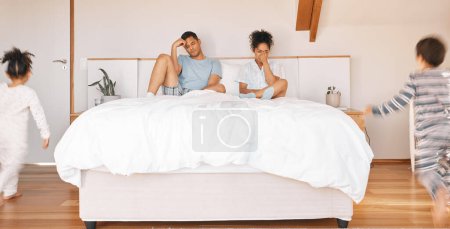 Photo for Family, stress and parents on bed with headache, anxiety or noise from running children with chaos. Kids, energy or mom and father in bedroom with burnout, depression or fatigue and crisis at home. - Royalty Free Image