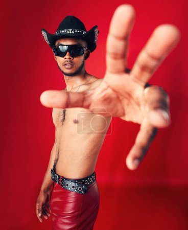 Photo for Man, portrait and fashion with grunge in studio or red background with unique cowboy aesthetic and sunglasses. Gen z, style and model with pride and hand in photography, retro or western clothing. - Royalty Free Image