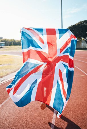 Téléchargez les photos : Drapeau britannique, athlète en course et vainqueur de course dans la célébration, la réalisation sportive et l'exercice d'entraînement sur piste. bannière du Royaume-Uni, victoire et patriotisme de la personne pour soutenir le pays dans le succès du champion. - en image libre de droit