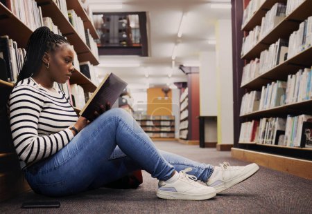 Photo for Research, book and a black woman in a library for reading, college knowledge or studying on the floor. Scholarship, student and an African girl at a university or a bookshop for education or learning. - Royalty Free Image