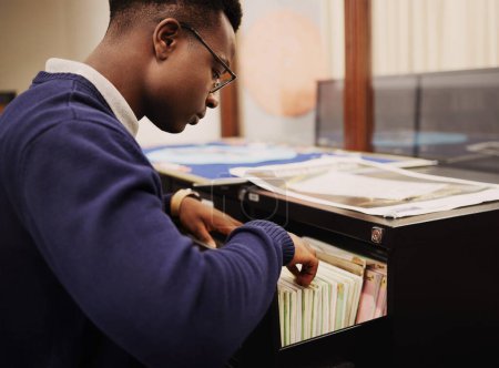Téléchargez les photos : Recherche scolaire, campus et un homme noir dans une bibliothèque pour la connaissance, l'apprentissage ou l'étude. Université, bourse et un jeune Africain ou étudiant à la recherche de livres pour la décision ou le choix. - en image libre de droit